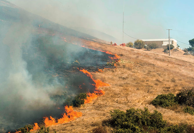 enlargeable photo of a fire raging in a field outside of a building
