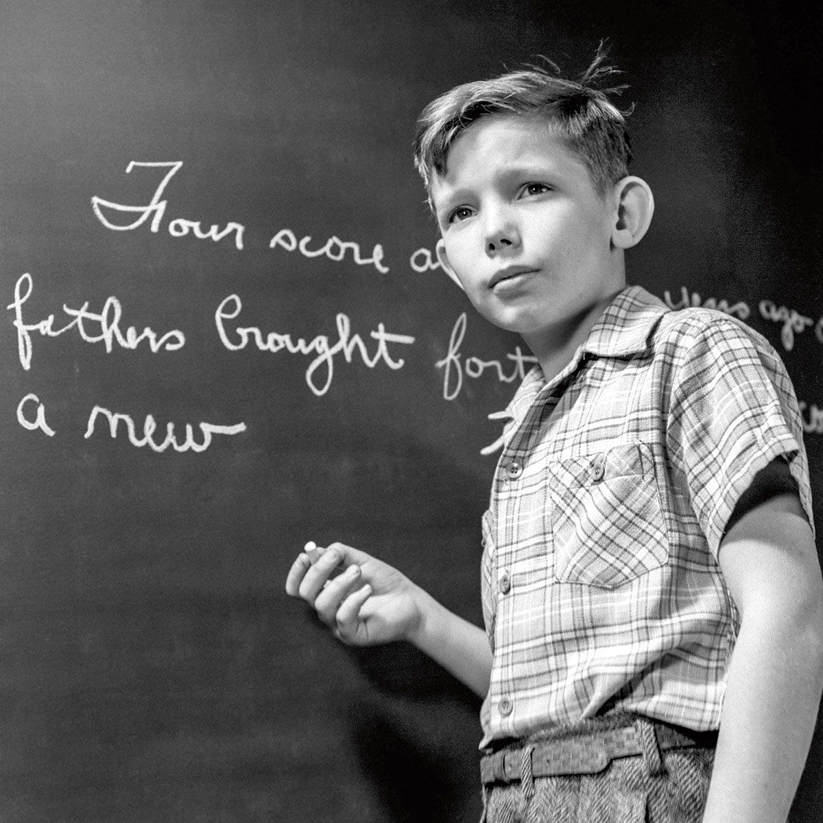 black and white photo of a student writing in cursive on a chalkboard